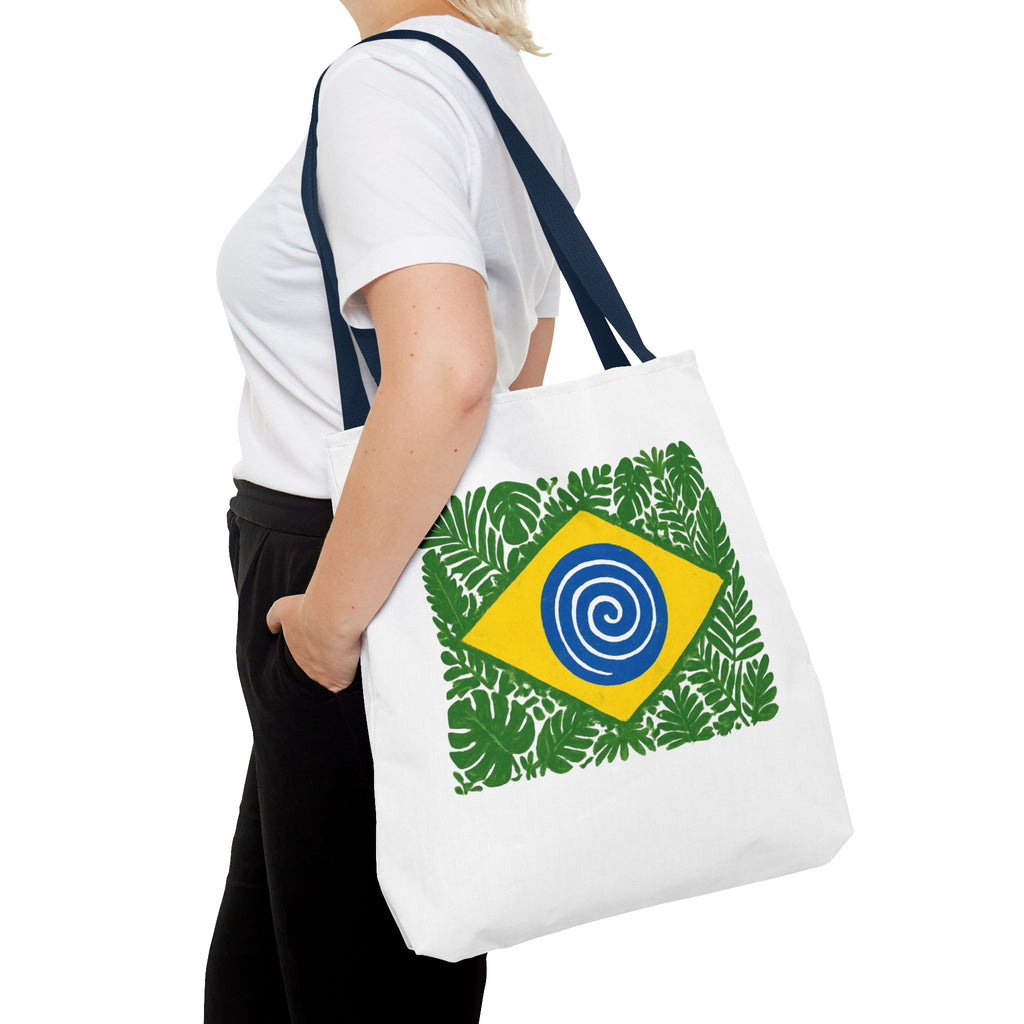 Person holding a white tote bag with a Brazilian flag design featuring leaves.